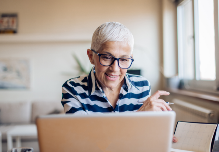 Smiling woman with glasses, smiling at laptop screen and managing her financial accounts.